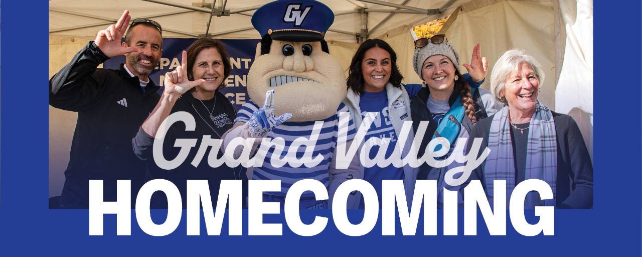 Alumni pose with Louie and give the anchor up sign during the Homecoming tailgate